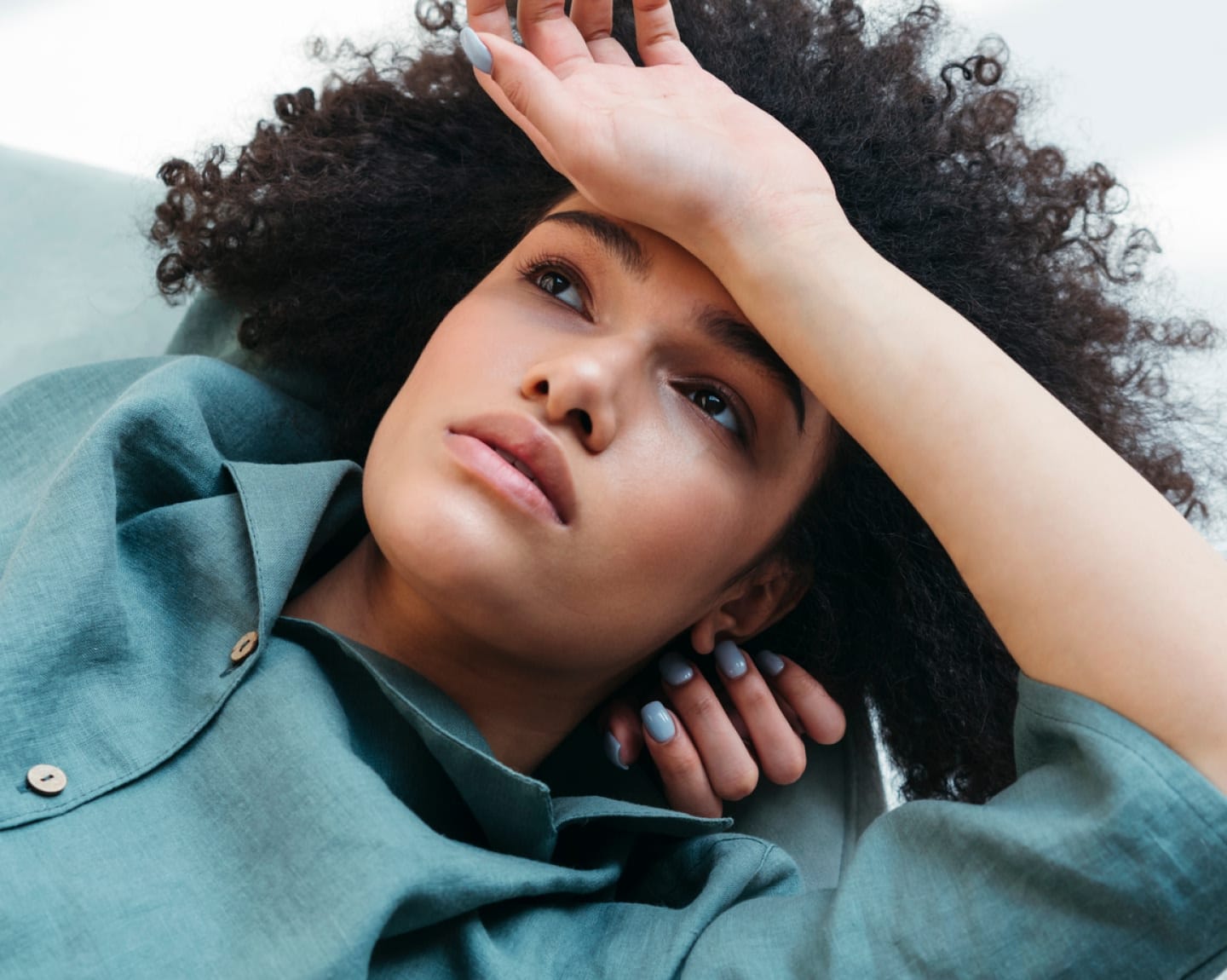 Woman laying down with a hand over her head