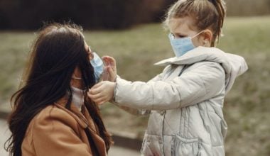 child fixing mask on mother's face