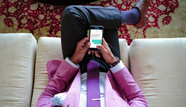 man sitting on couch texting Talkspace therapist