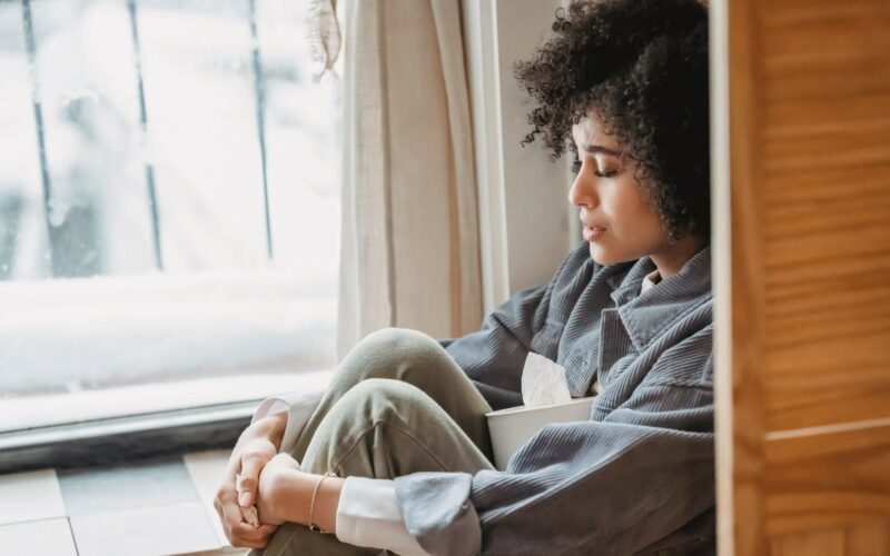 woman sitting in window looking sad