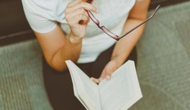 woman holding book and glasses