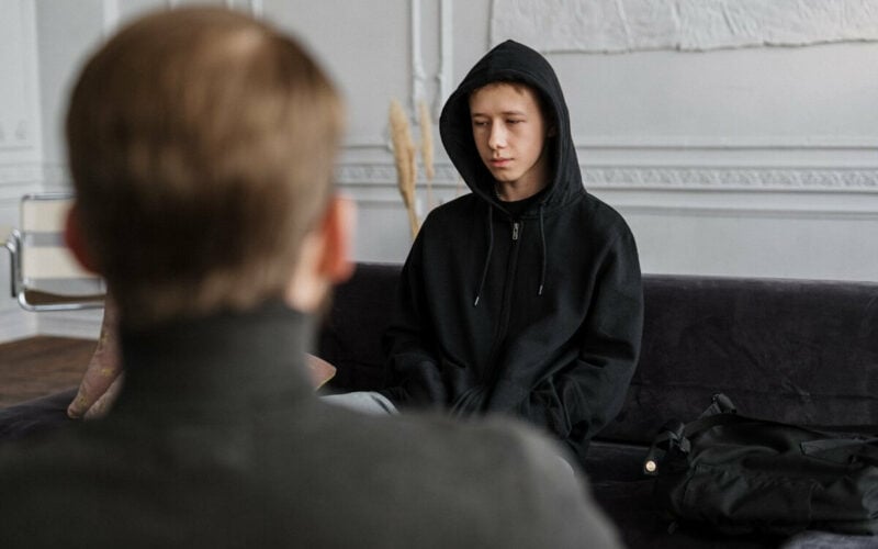 boy in black hoodie sitting across from man