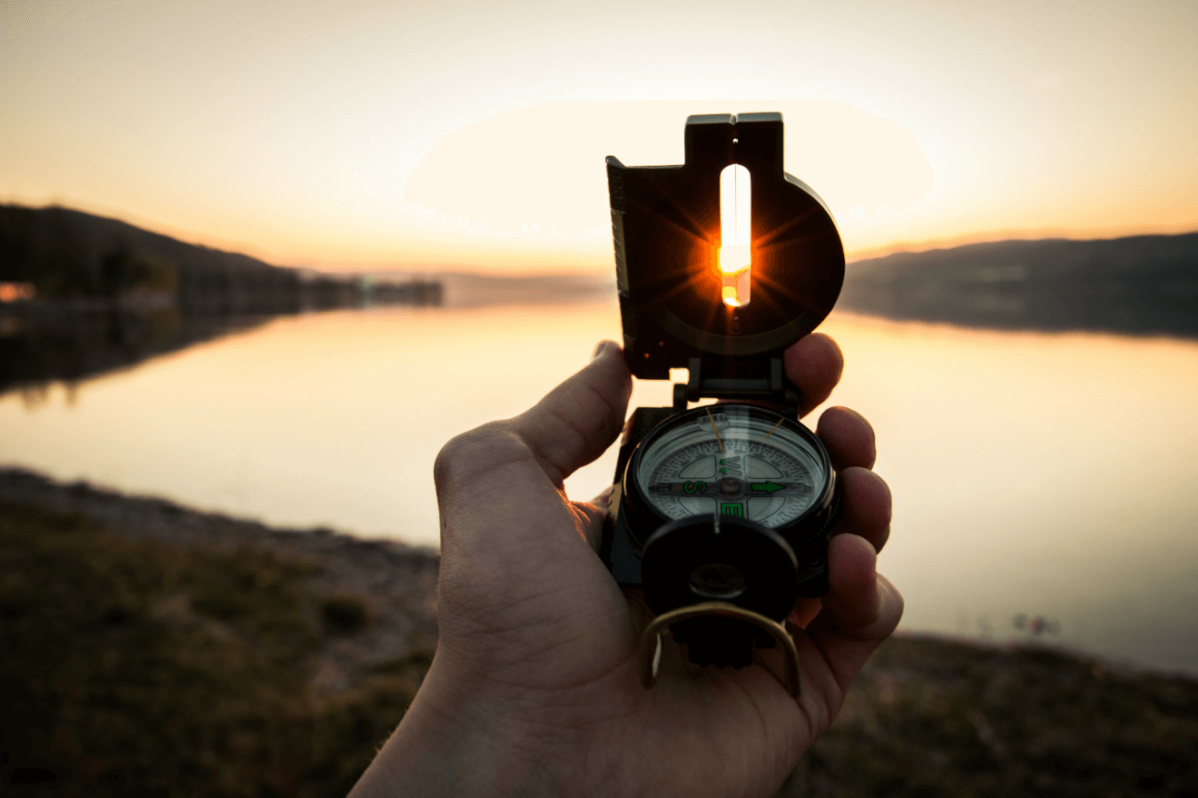 compass facing a lake at sunset